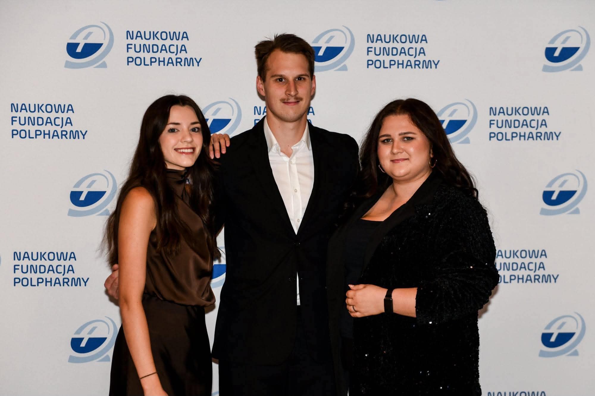 trzy osoby pozują na ściance Polpharmy